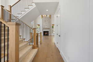 Interior space with a large fireplace, baseboards, wood-type flooring, a notable chandelier, and recessed lighting