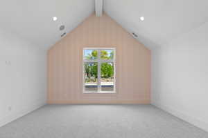 Additional living space featuring lofted ceiling with beams, carpet, and visible vents