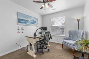 Home office featuring carpet flooring, visible vents, baseboards, and a ceiling fan