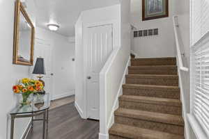 Staircase featuring visible vents, baseboards, and wood finished floors