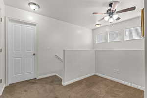Carpeted spare room with baseboards, a textured ceiling, and ceiling fan