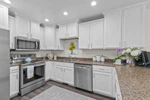 Kitchen with a sink, white cabinetry, and stainless steel appliances