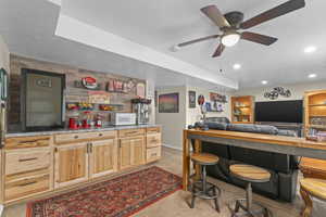 Bar featuring recessed lighting, white microwave, ceiling fan, light colored carpet, and bar