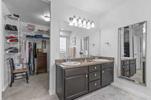Bathroom with a sink, a spacious closet, double vanity, and baseboards