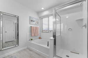 Full bath with a shower stall, a bath, and baseboards