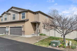 Craftsman-style house with a garage, stucco siding, stone siding, fence, and concrete driveway