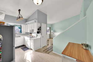 Kitchen with freestanding refrigerator, light wood-style flooring, white cabinetry, lofted ceiling, and electric stove