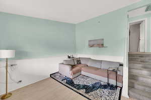 Living room with stairway, a wainscoted wall, and wood finished floors