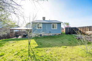 Back of property featuring a yard, a fenced backyard, and a chimney