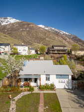 View of front facade featuring a mountain view, fence, and driveway