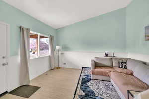 Living area with lofted ceiling, wainscoting, and wood finished floors
