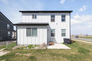 Back of property with board and batten siding and a yard