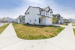 View of side of property featuring board and batten siding, a yard, an attached garage, a mountain view, and a residential view