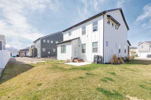 Back of property featuring entry steps, board and batten siding, fence, and a lawn
