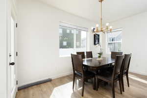 Dining area featuring baseboards, light wood-type flooring, and an inviting chandelier