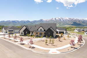 View of front facade with a mountain view, board and batten siding, a garage, driveway, and roof with shingles