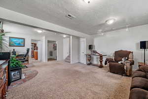 Carpeted living area featuring rail lighting, a textured ceiling, stairs, washer / dryer, and visible vents