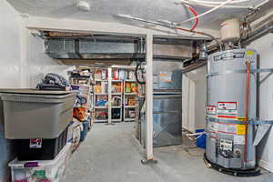 Unfinished below grade area featuring a textured ceiling and water heater