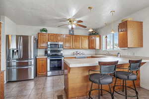 Kitchen featuring a peninsula, visible vents, a breakfast bar, appliances with stainless steel finishes, and a sink