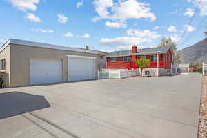 View of front of property featuring stucco siding, a chimney, a fenced front yard, brick siding, and a garage