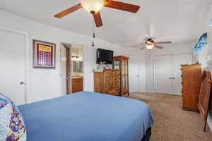 Bedroom with ensuite bathroom, a textured ceiling, a ceiling fan, carpet floors, and a sink
