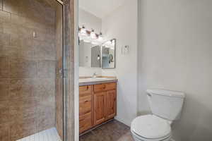 Full bathroom featuring vanity, baseboards, a stall shower, tile patterned floors, and toilet