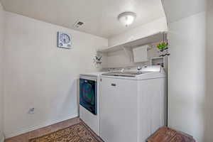 Laundry area featuring separate washer and dryer, tile patterned floors, a textured ceiling, visible vents, and laundry area