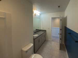 Bathroom featuring vanity, baseboards, tile patterned flooring, a textured ceiling, and toilet