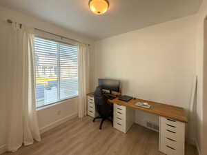 Office area with light wood-style flooring, baseboards, and visible vents