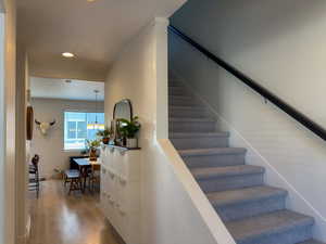 Stairway with a textured ceiling, wood finished floors, and recessed lighting