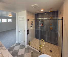 Full bath featuring visible vents, a textured ceiling, baseboards, and a stall shower