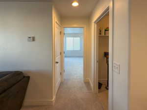 Corridor featuring light colored carpet and baseboards