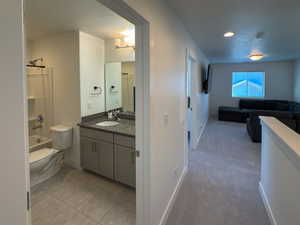 Full bathroom with a textured ceiling, vanity, toilet, tile patterned floors, and baseboards