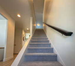 Stairs with wood finished floors, baseboards, and recessed lighting
