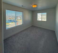 Unfurnished room with a textured ceiling, baseboards, visible vents, and carpet floors