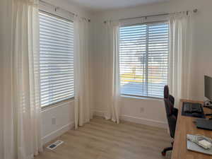 Office space with light wood-style flooring, baseboards, and visible vents