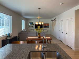 Kitchen with light wood-style floors, a healthy amount of sunlight, a sink, and a notable chandelier
