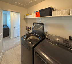 Washroom with laundry area, light colored carpet, attic access, light tile patterned flooring, and washer and dryer