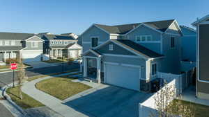 View of front of home with concrete driveway, a residential view, stone siding, and fence