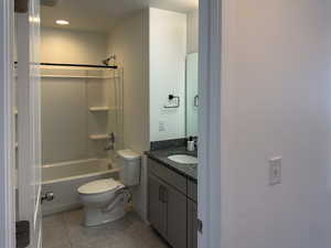 Bathroom featuring washtub / shower combination, tile patterned flooring, vanity, and toilet