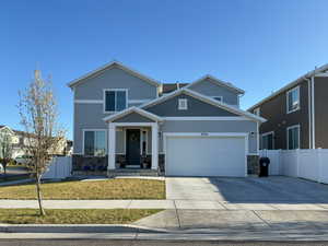 View of front of house with driveway, stone siding, fence, and an attached garage