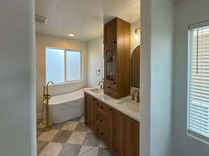 Bathroom with a soaking tub, double vanity, a sink, and visible vents