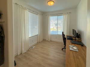 Office space with visible vents, baseboards, and light wood-type flooring