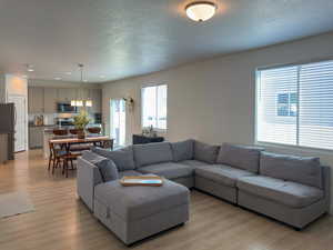 Living area with a textured ceiling, light wood finished floors, and recessed lighting