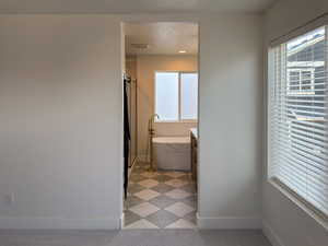 Bathroom with visible vents, baseboards, a textured ceiling, and a soaking tub