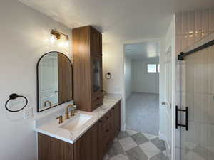 Bathroom featuring a textured ceiling, double vanity, a sink, and baseboards