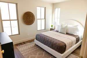 Bedroom with wood finished floors, baseboards, and multiple windows