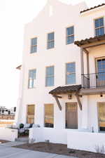 View of front of property featuring a balcony, stucco siding, and a tiled roof