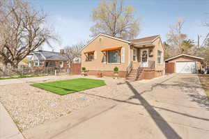 Cottage style rambler homewith faux grass, stucco siding, a detached garage, fence, and an double driveway