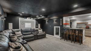 Home theater room with baseboards, wet bar, a textured ceiling, recessed lighting, and light colored carpet